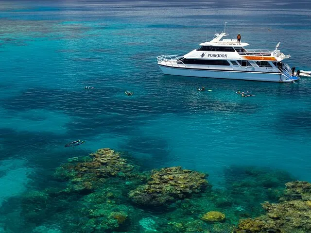 Barco Poseidon rodeado de practicantes de snorkel que exploran las claras aguas azules del arrecife
